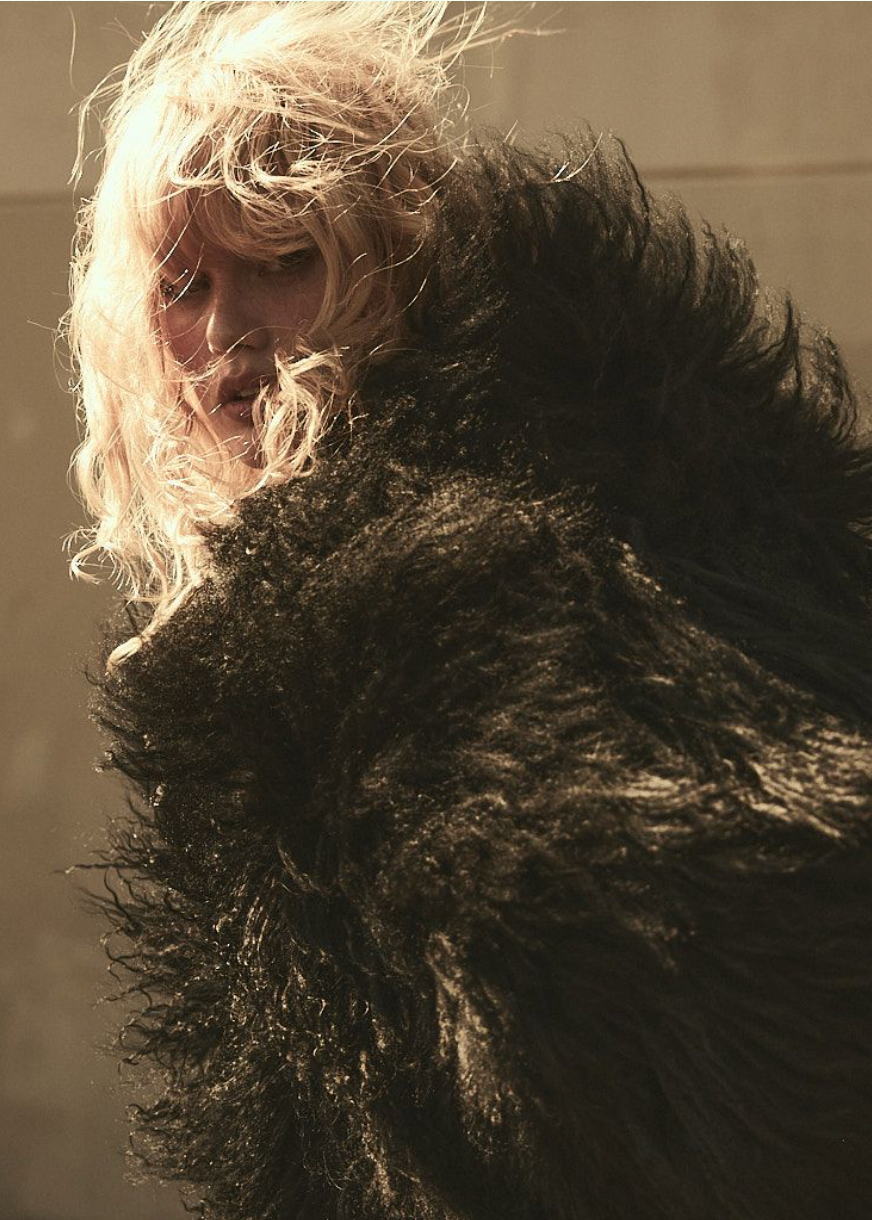 Model wearing a long curly-haired shearling fur jacket.