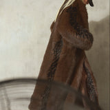 A woman wearing a long brown and black faux fur coat, styled with a black wool cap and black high heels.