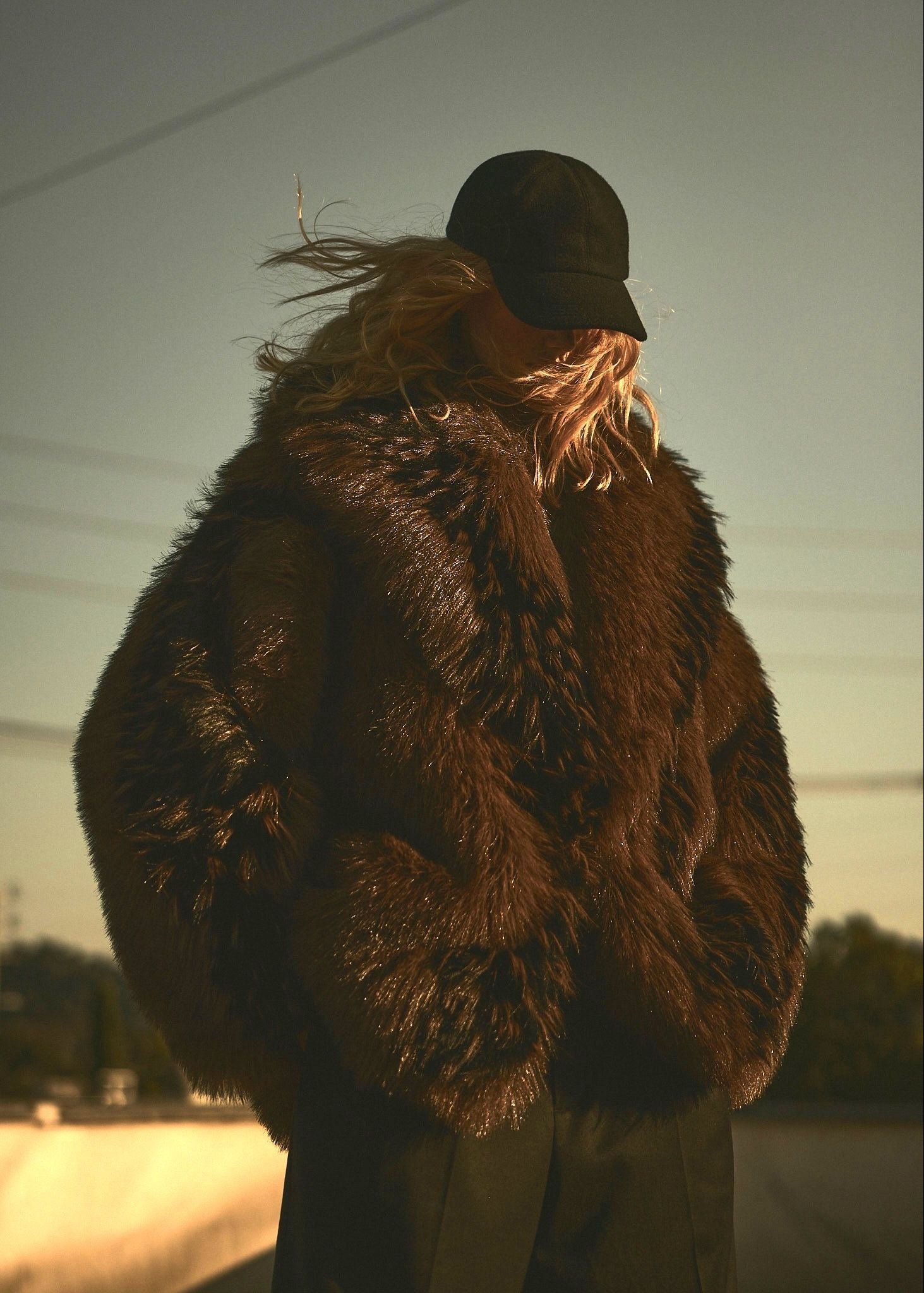 Model wearing a brown and black faux fur jacket with a black wool cap.
