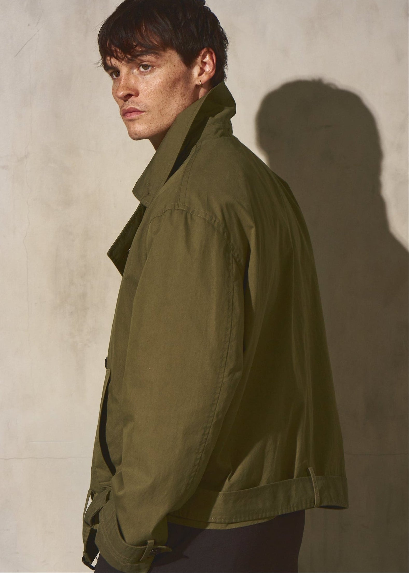 Man wearing a green jacket against a plain background
