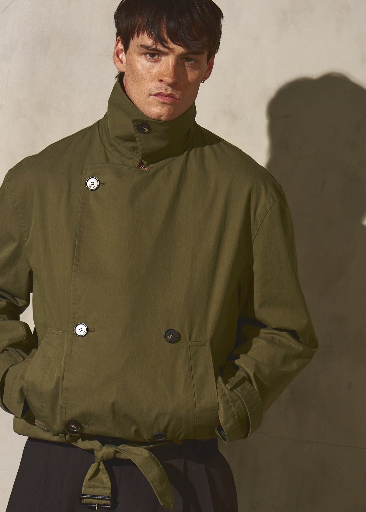 Man wearing a green jacket against a neutral background